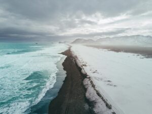 Side-by-side view of Iceland in summer with green landscapes and winter with snow and northern lights in the sky.